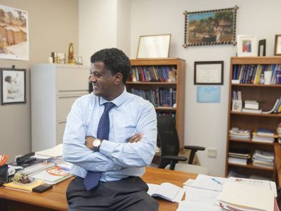 Mulugeta Gebregziabher, Ph.D., smiles in his office on Cannon Street. Born in Ethiopia, “Dr. G,” as many of his students call him, has returned to visit his homeland nearly every year for the past 20 years. Photo by Sarah Pack.